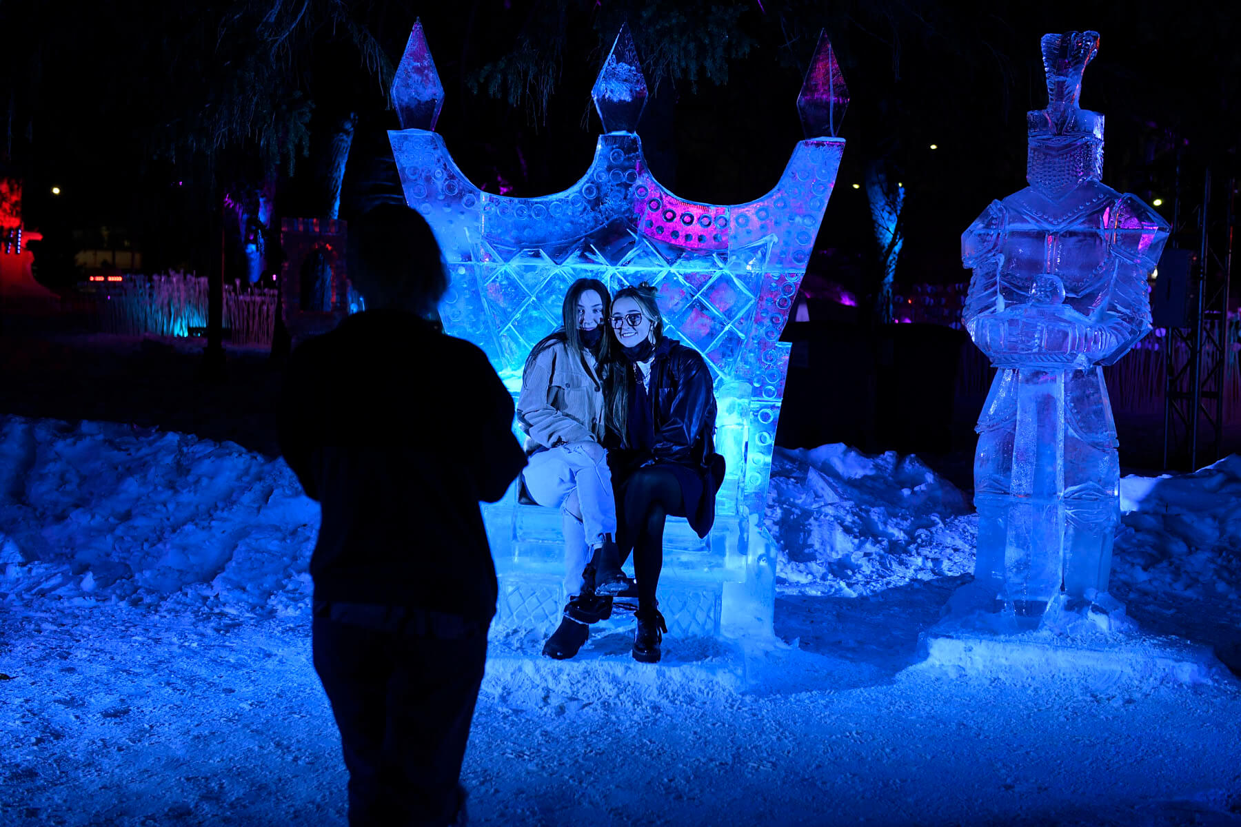 Women posing on an ice sculpture throne during Glow at REAL
