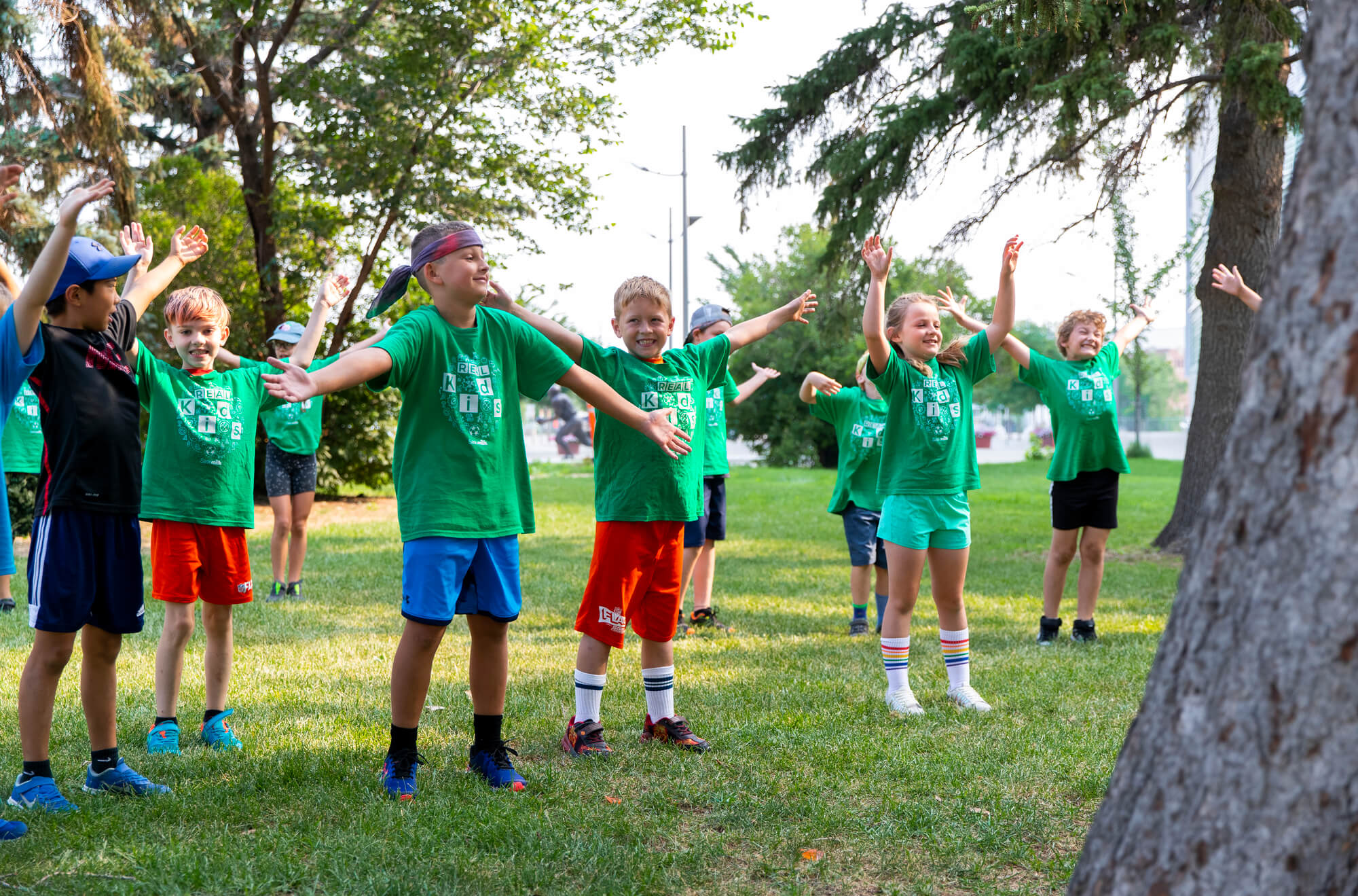 Kid's doing jumping jacks outside in Confederation Park during a summer Kids Camp