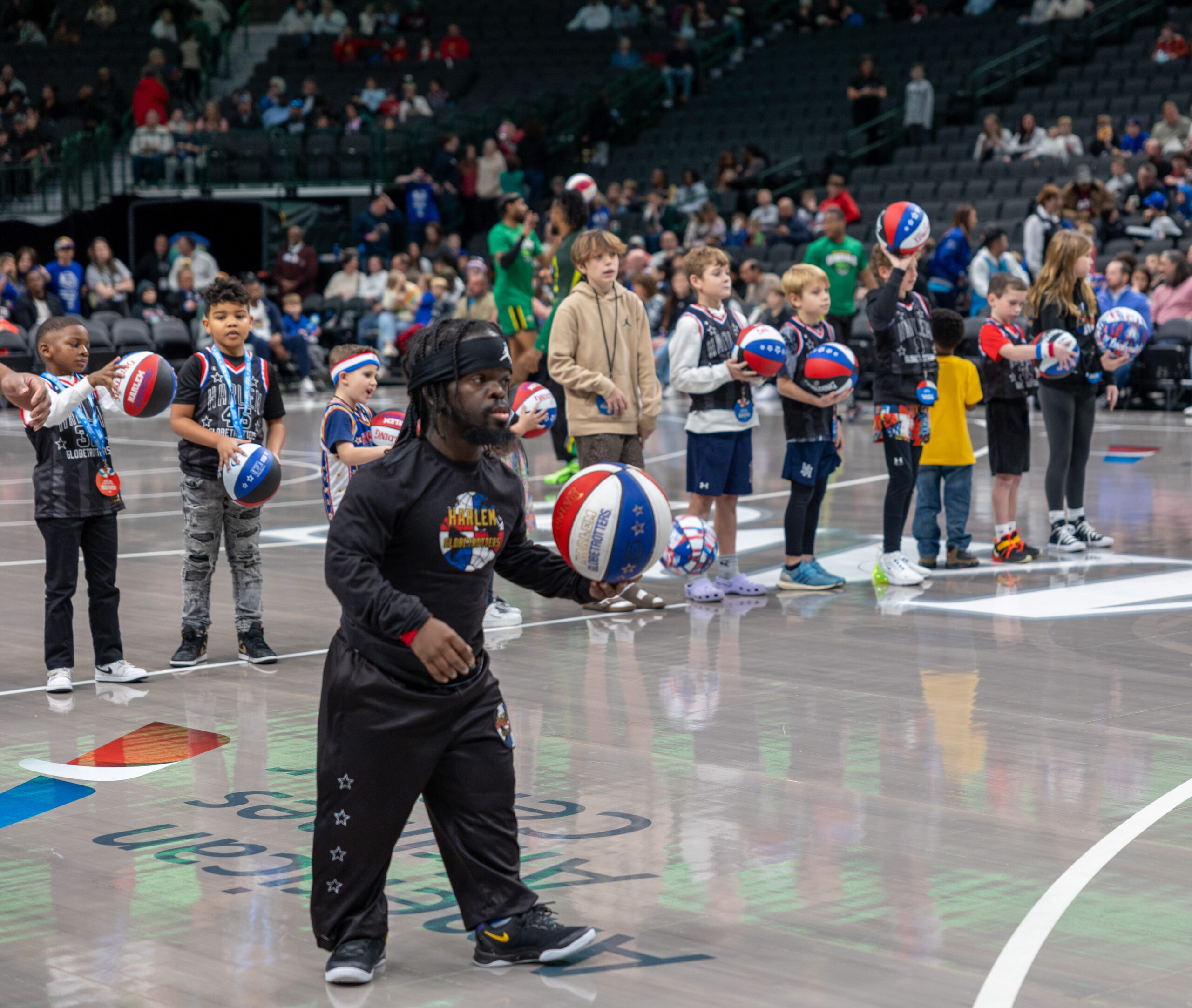 Basketball players perform tricks on court.
