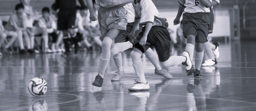 Children playing indoor soccer with focus on ball.