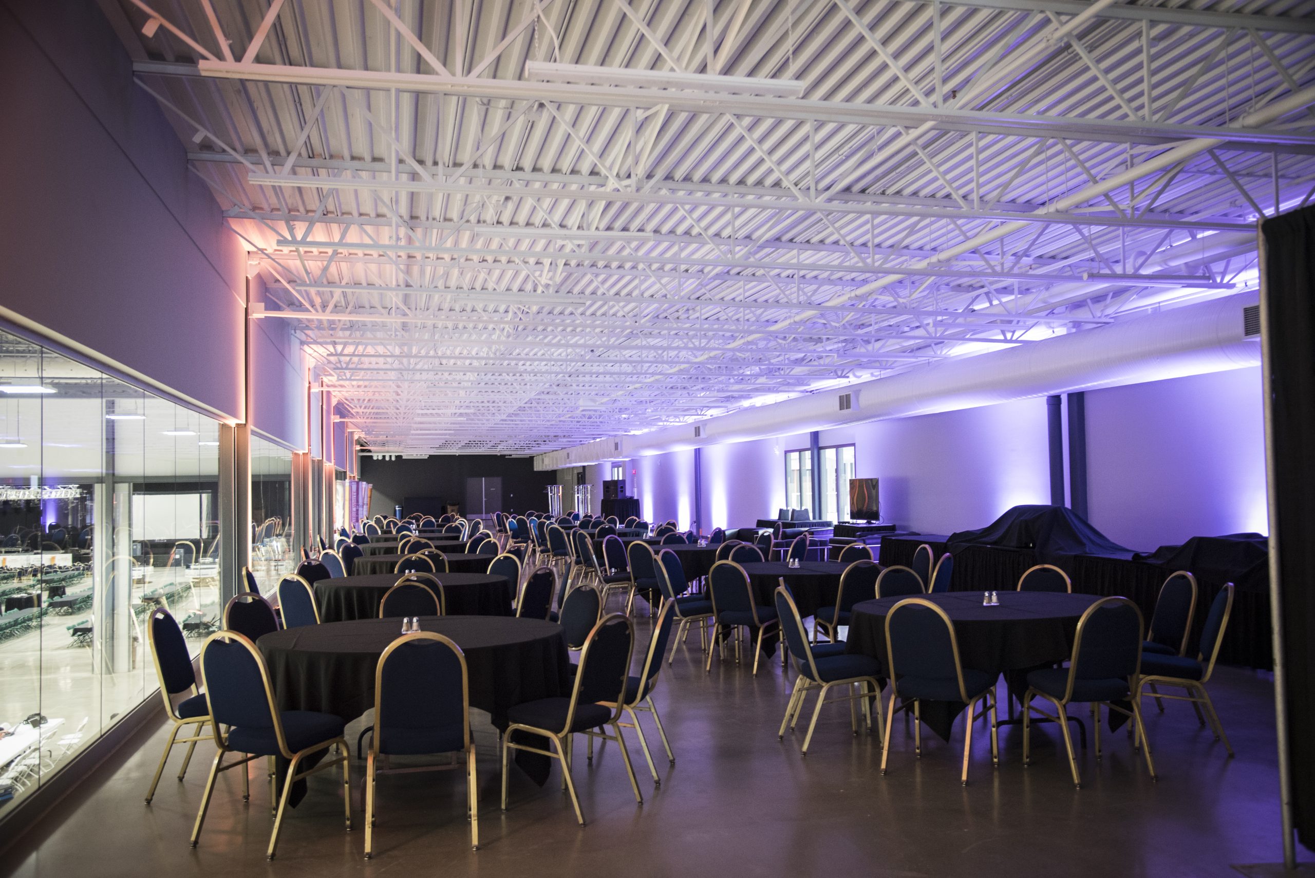 Large empty banquet hall with round tables and chairs.
