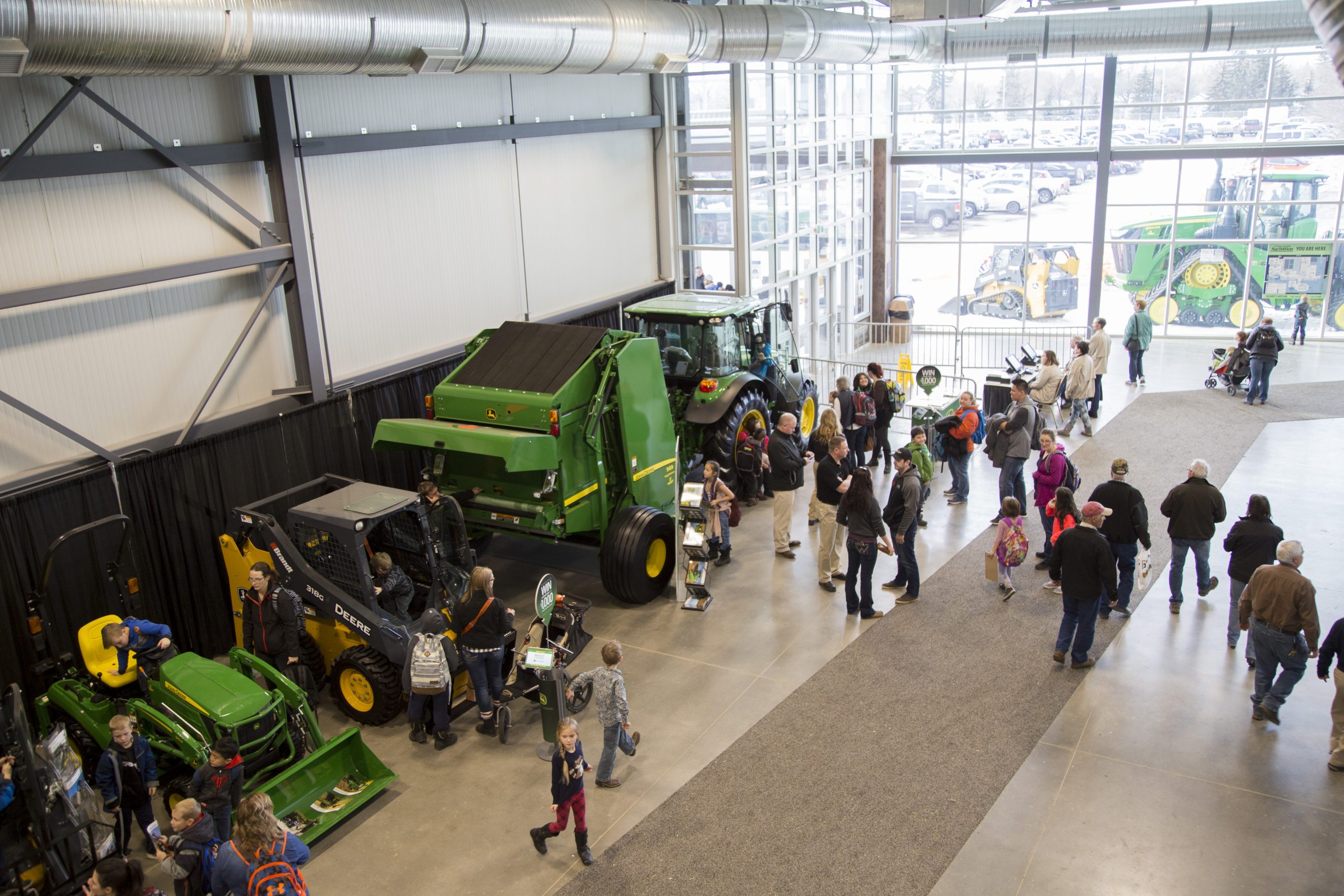 People viewing tractors inside a large showroom.