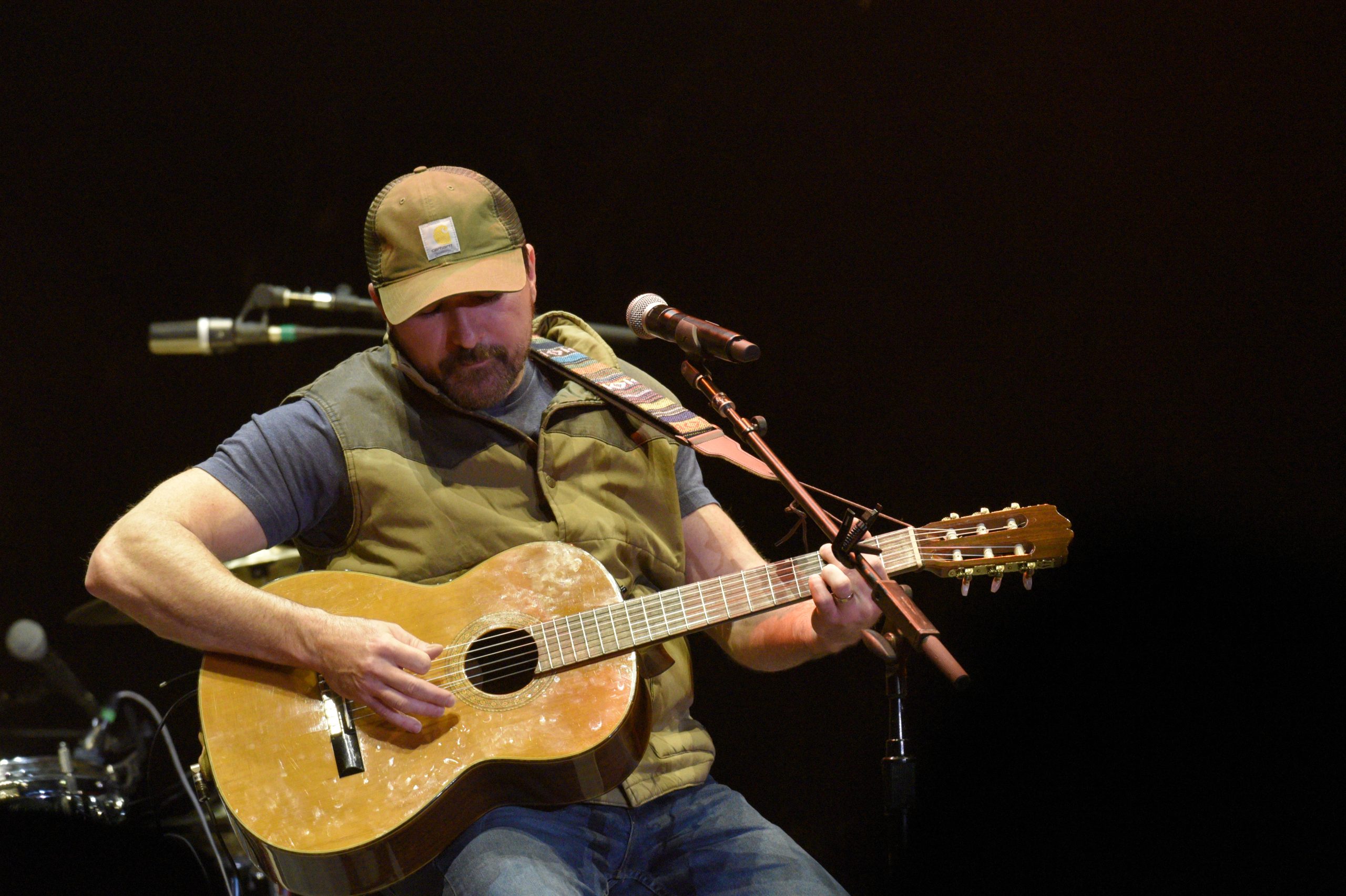 Musician playing acoustic guitar on stage