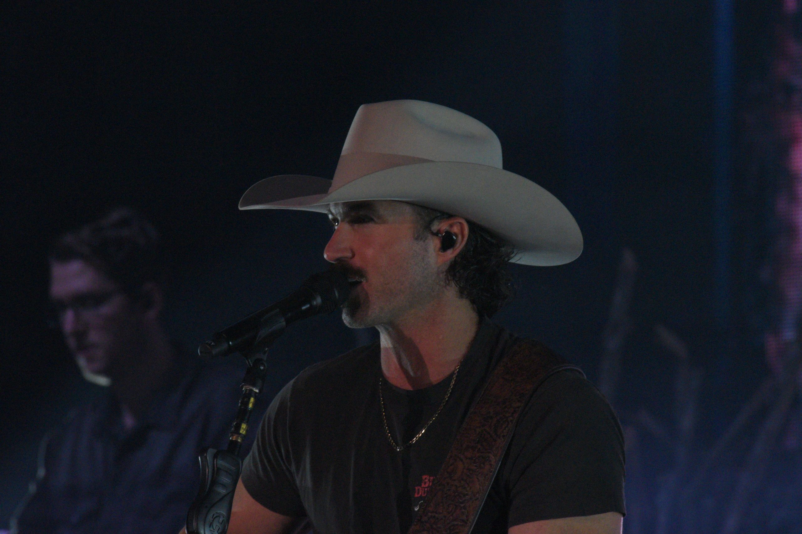 Singer with cowboy hat performing on stage.