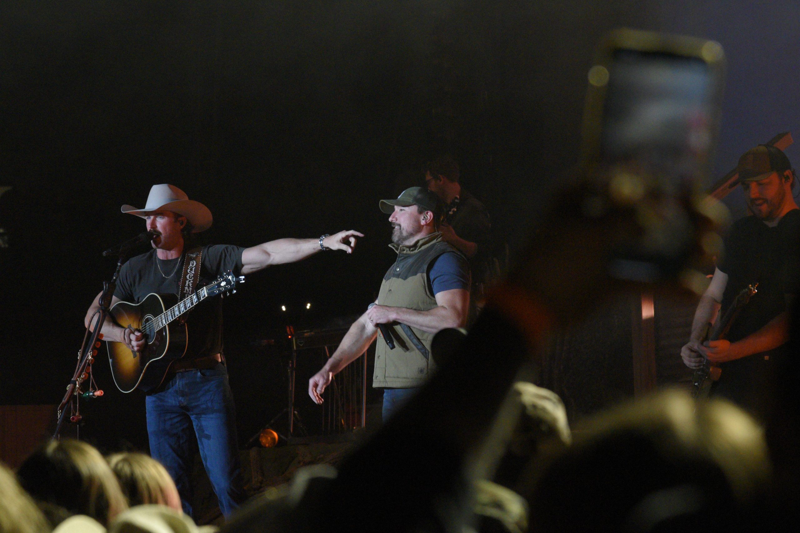 Country band performing on stage with crowd.