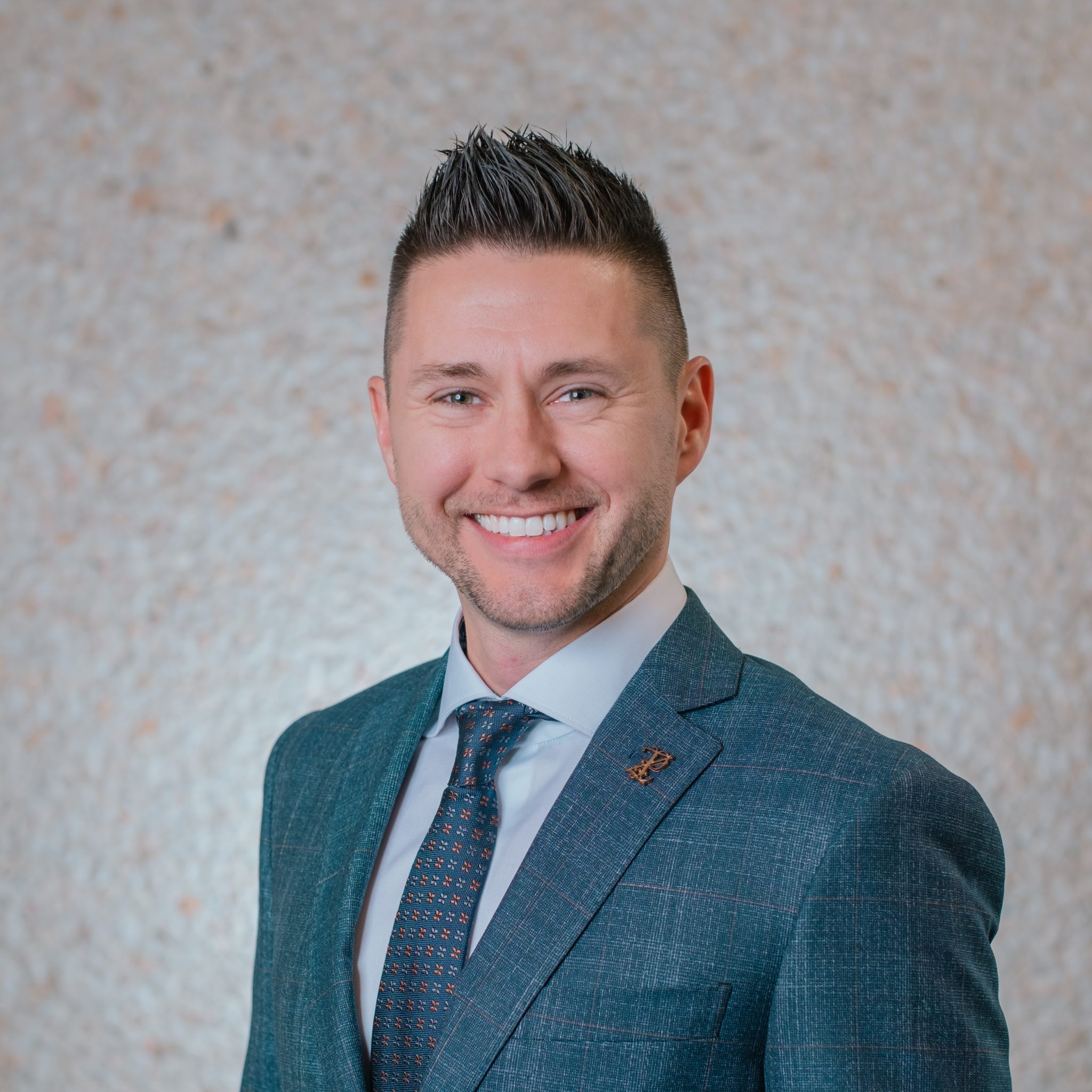 Smiling man in a suit with textured background.