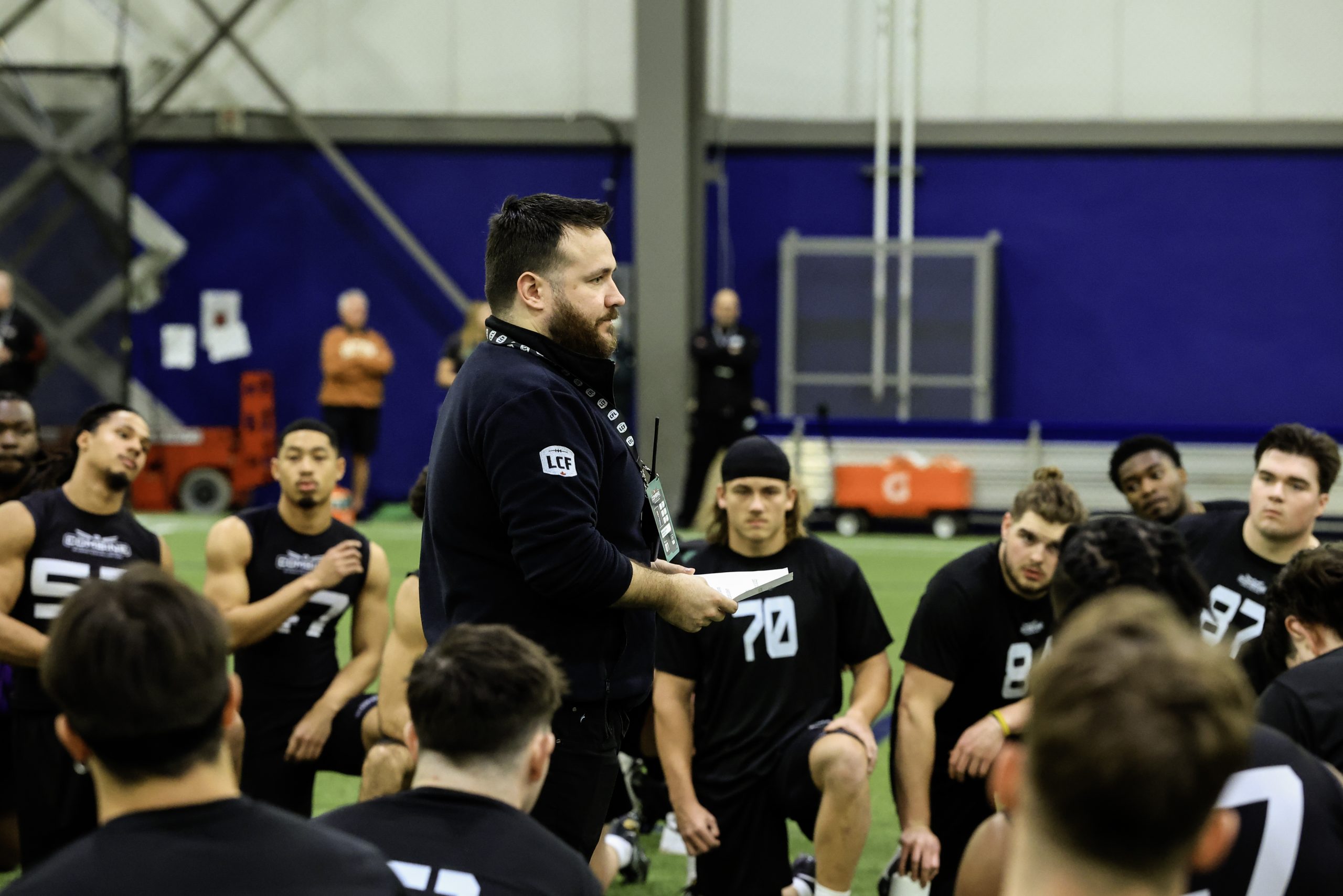 Coach addresses football players in training session.