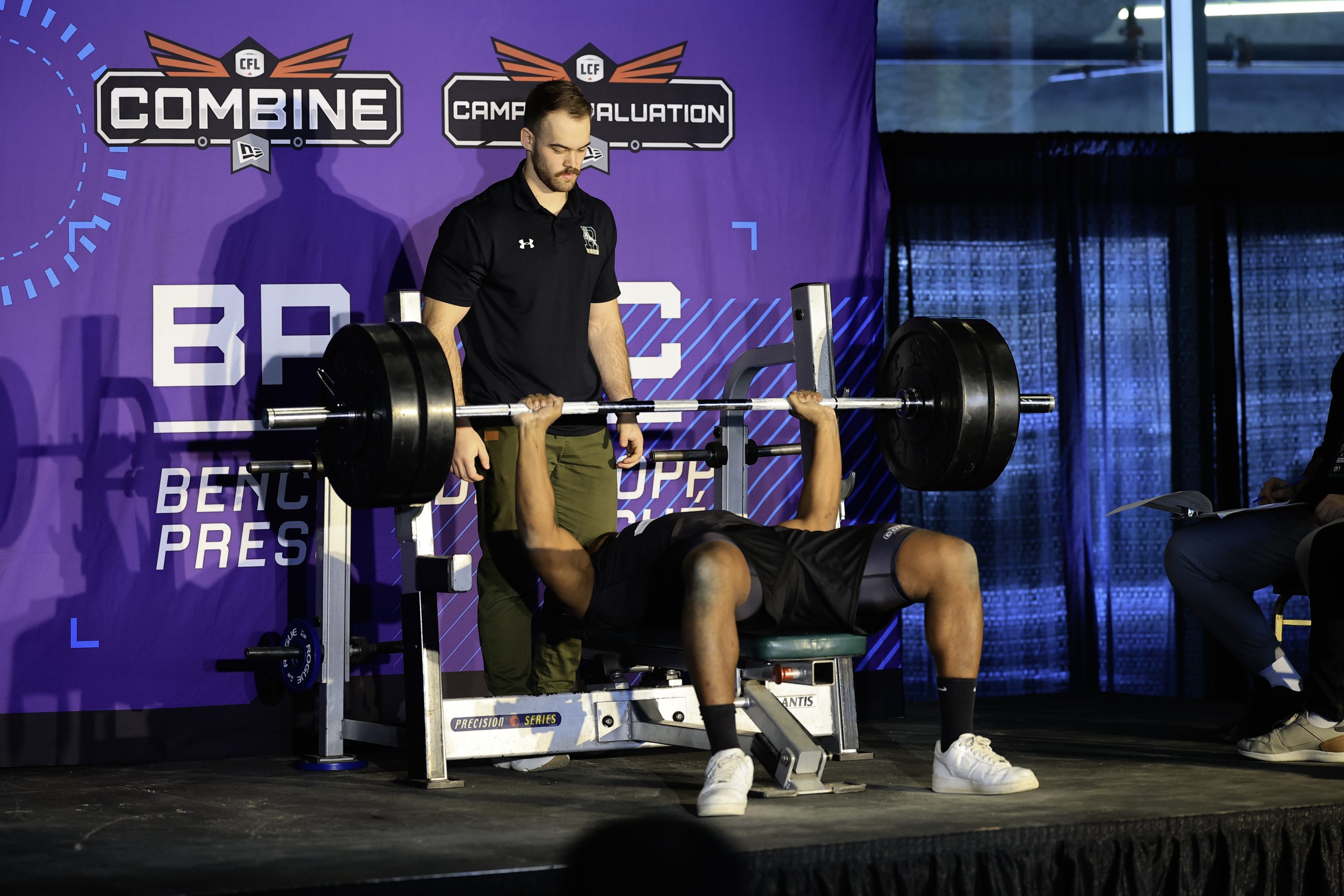 Athlete performing bench press at sports combine event.