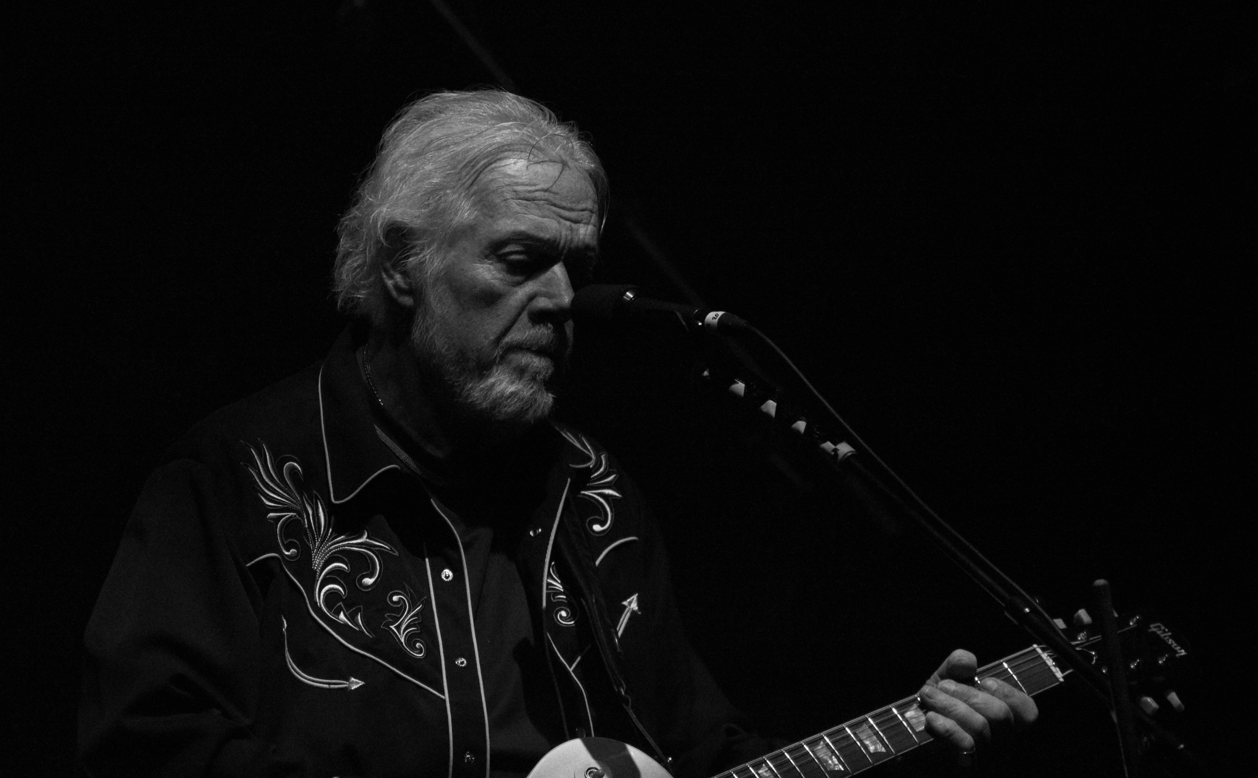 Man playing guitar on stage in black and white.