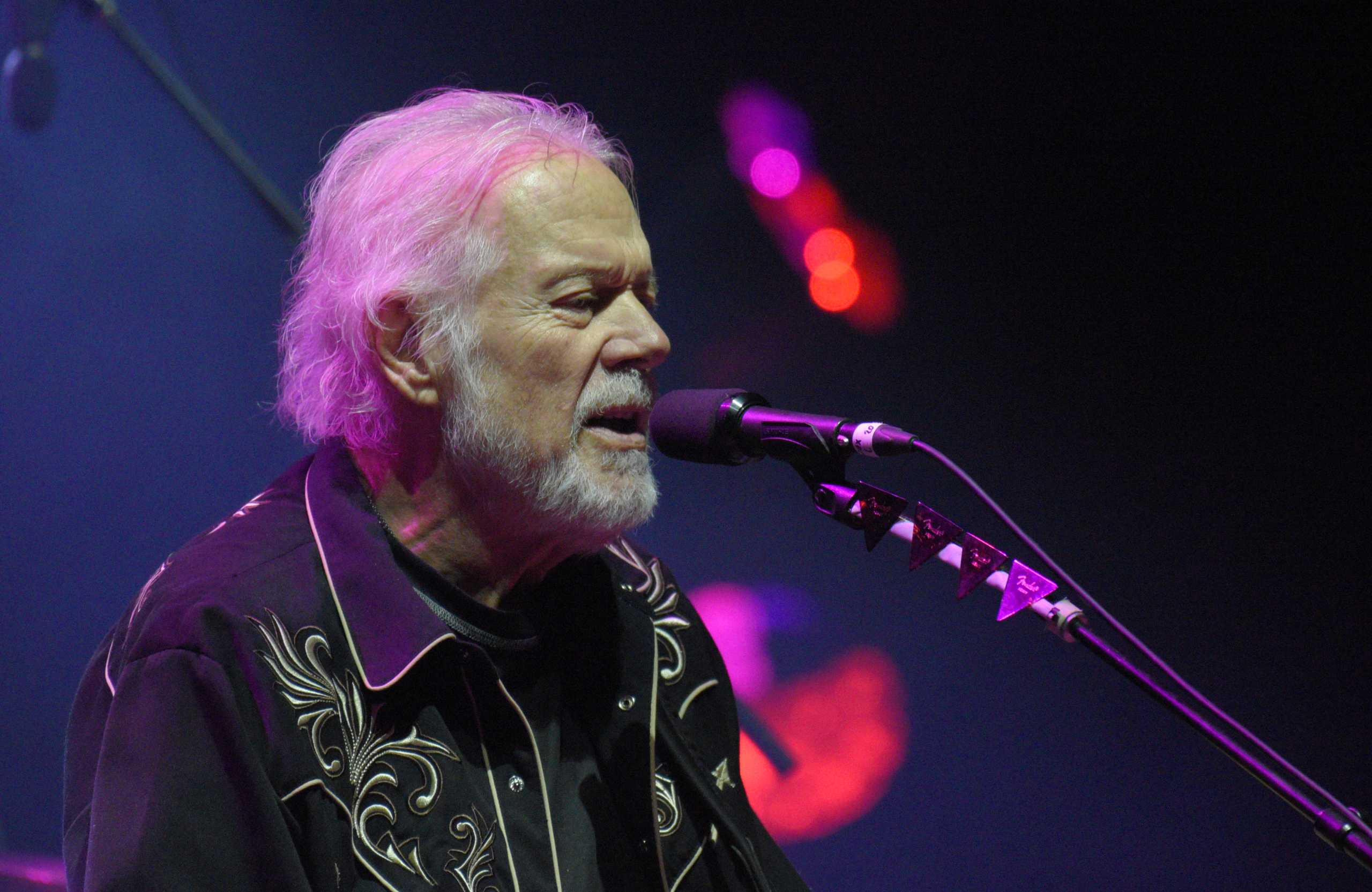 Musician singing on stage with microphone.