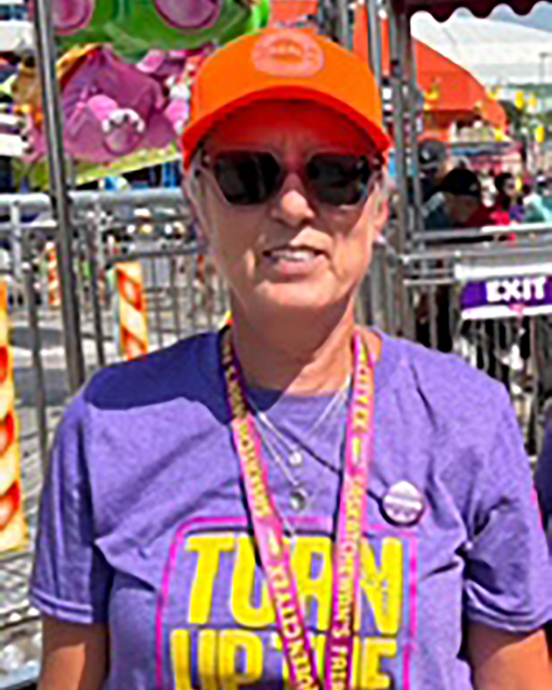 Person at a fair wearing purple shirt and orange hat