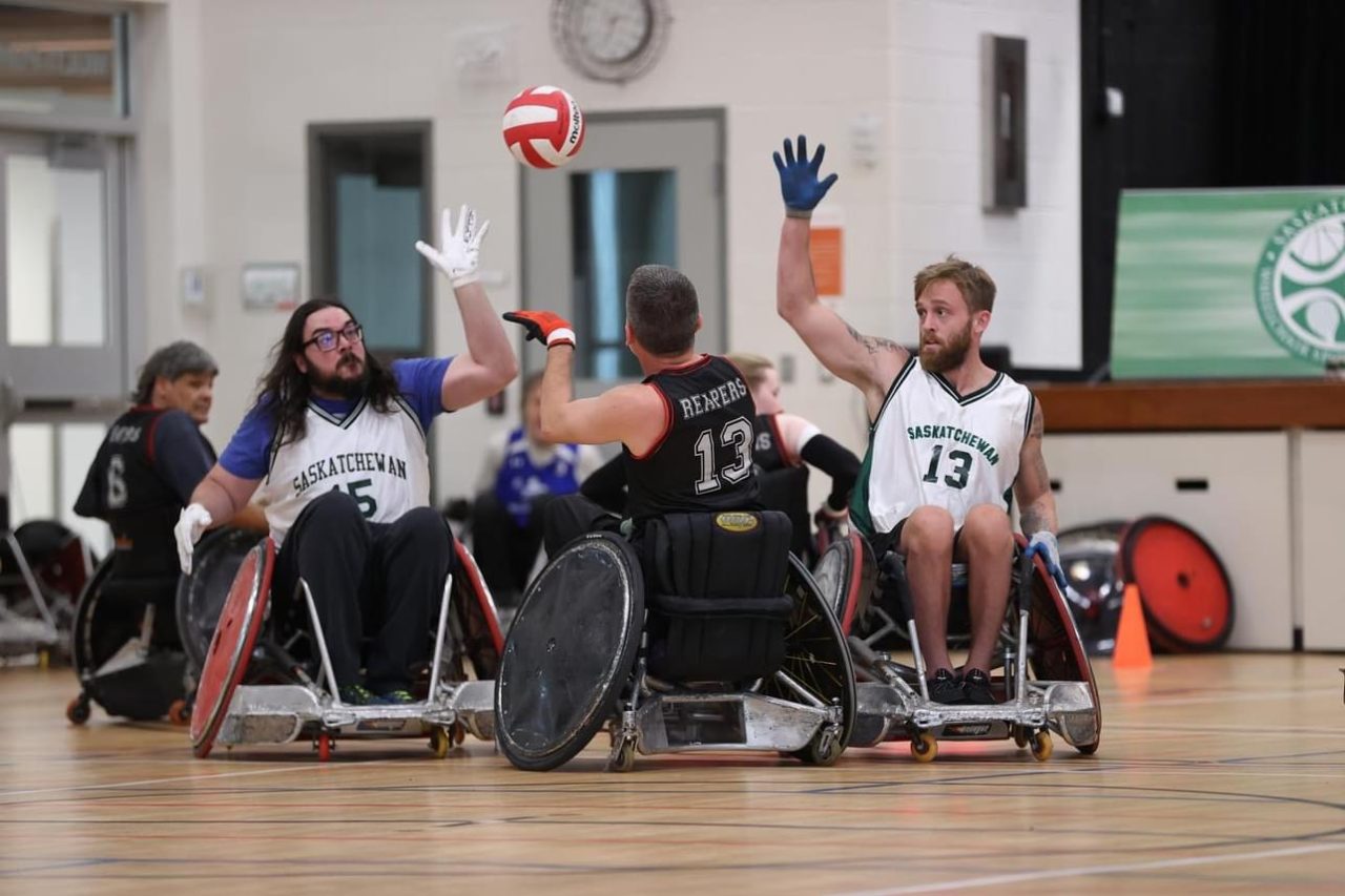 Wheelchair rugby players compete in gymnasium.