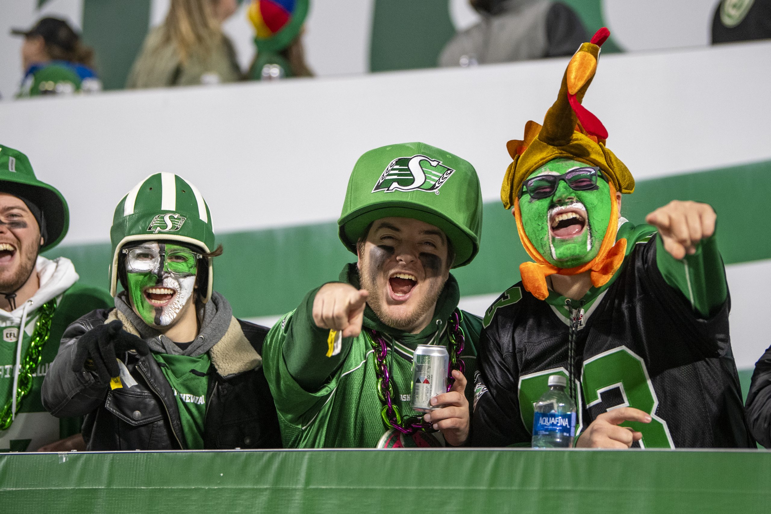 Enthusiastic football fans in painted faces, cheering.