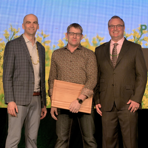 Three men at award ceremony on stage