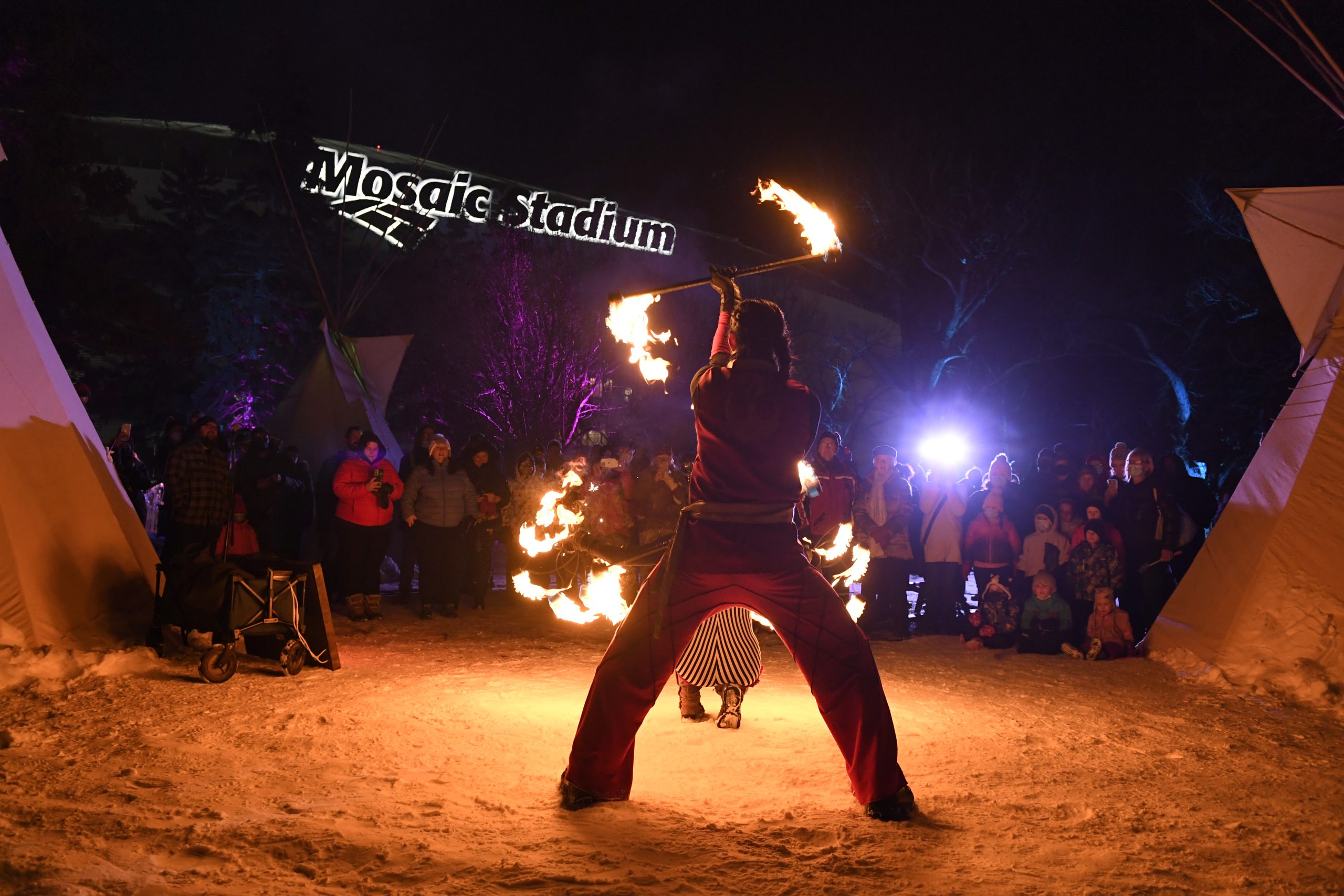 Fire performer at night in Mosaic Stadium.