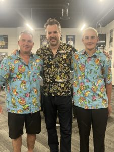 Three people in colorful Hawaiian shirts smiling.
