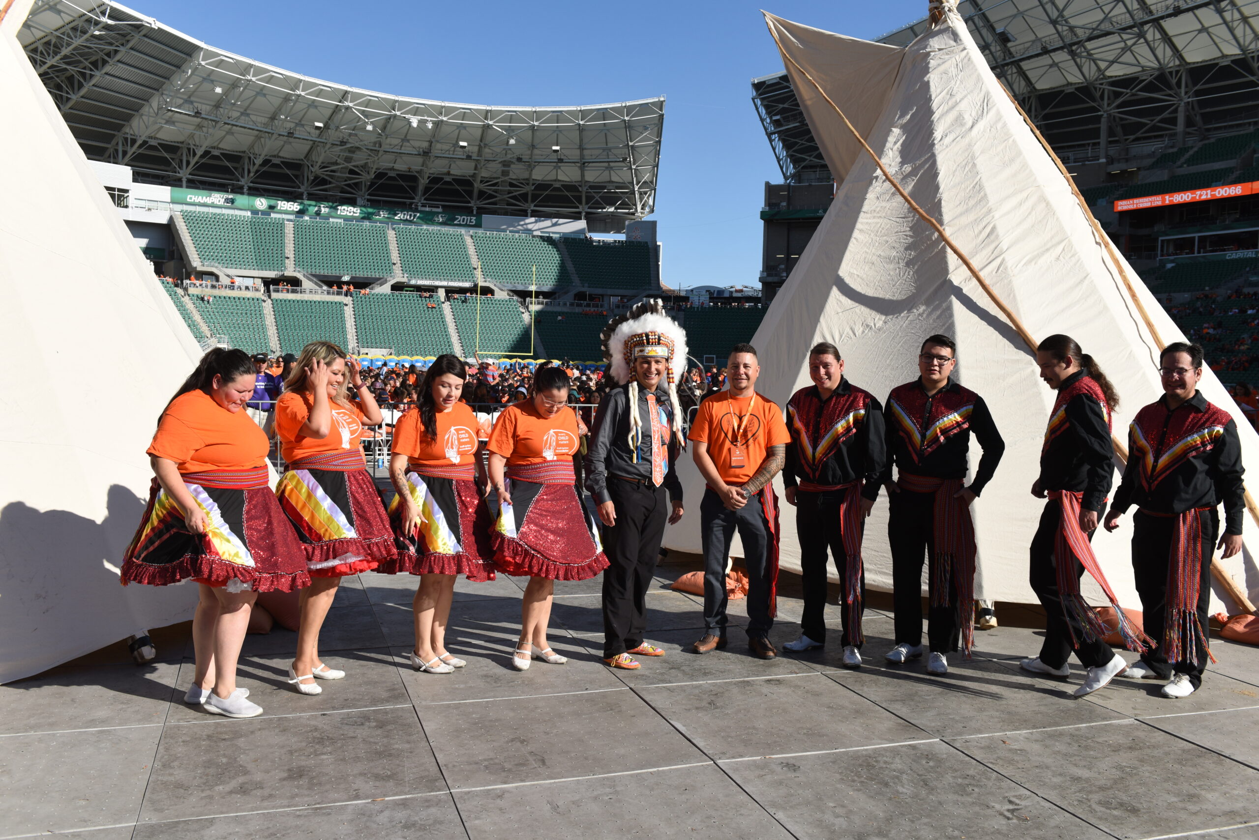 People in traditional attire near large outdoor tents.