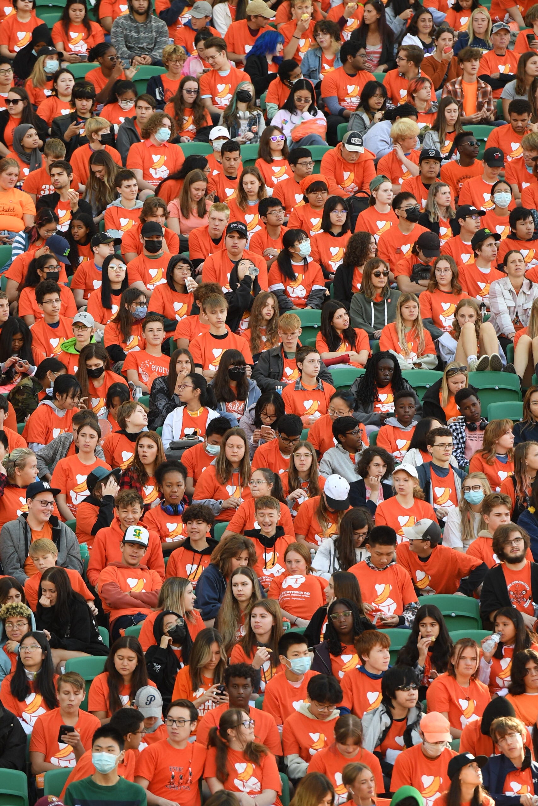 Large group wearing orange shirts in stadium seats.