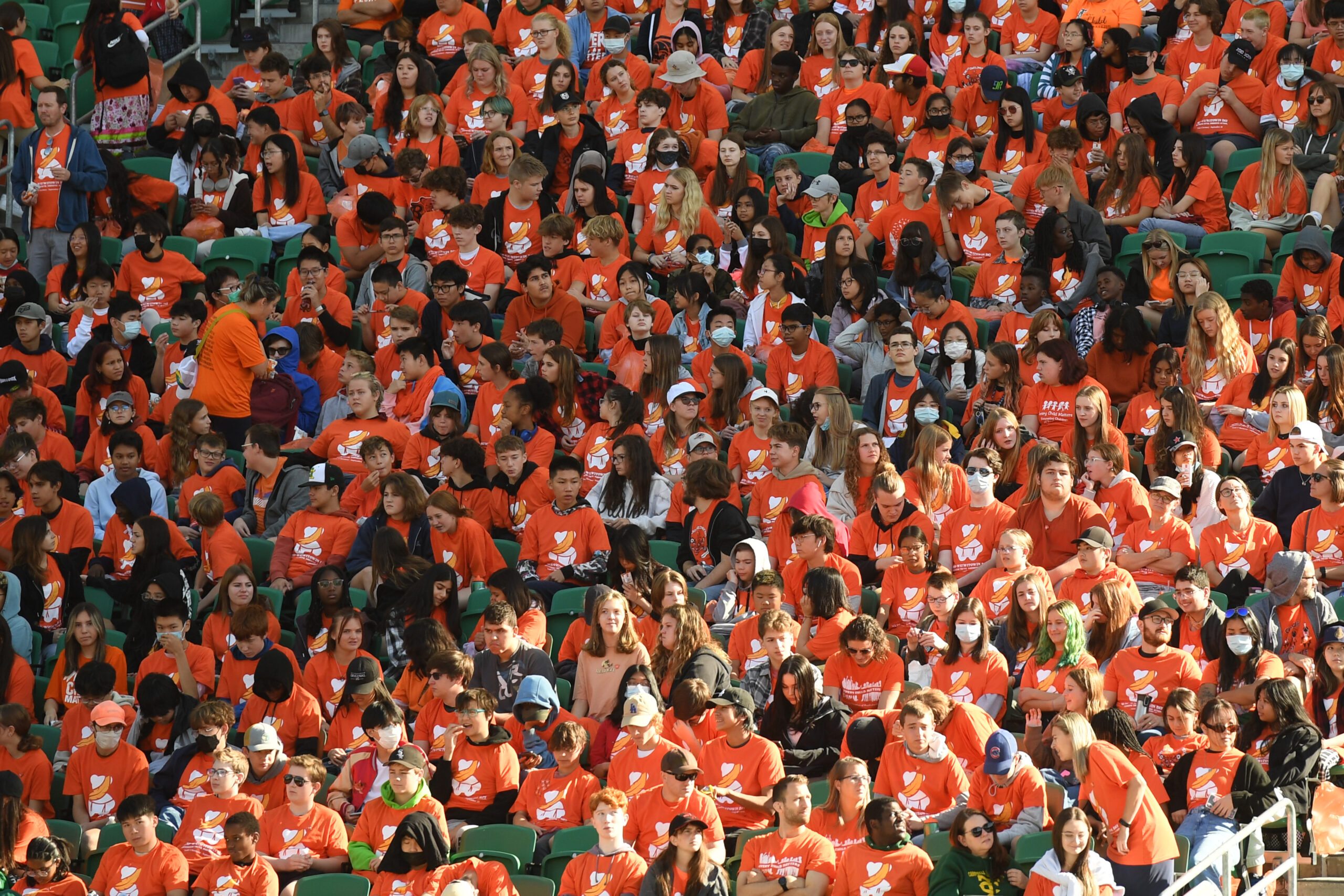 Crowd in orange shirts at stadium event.