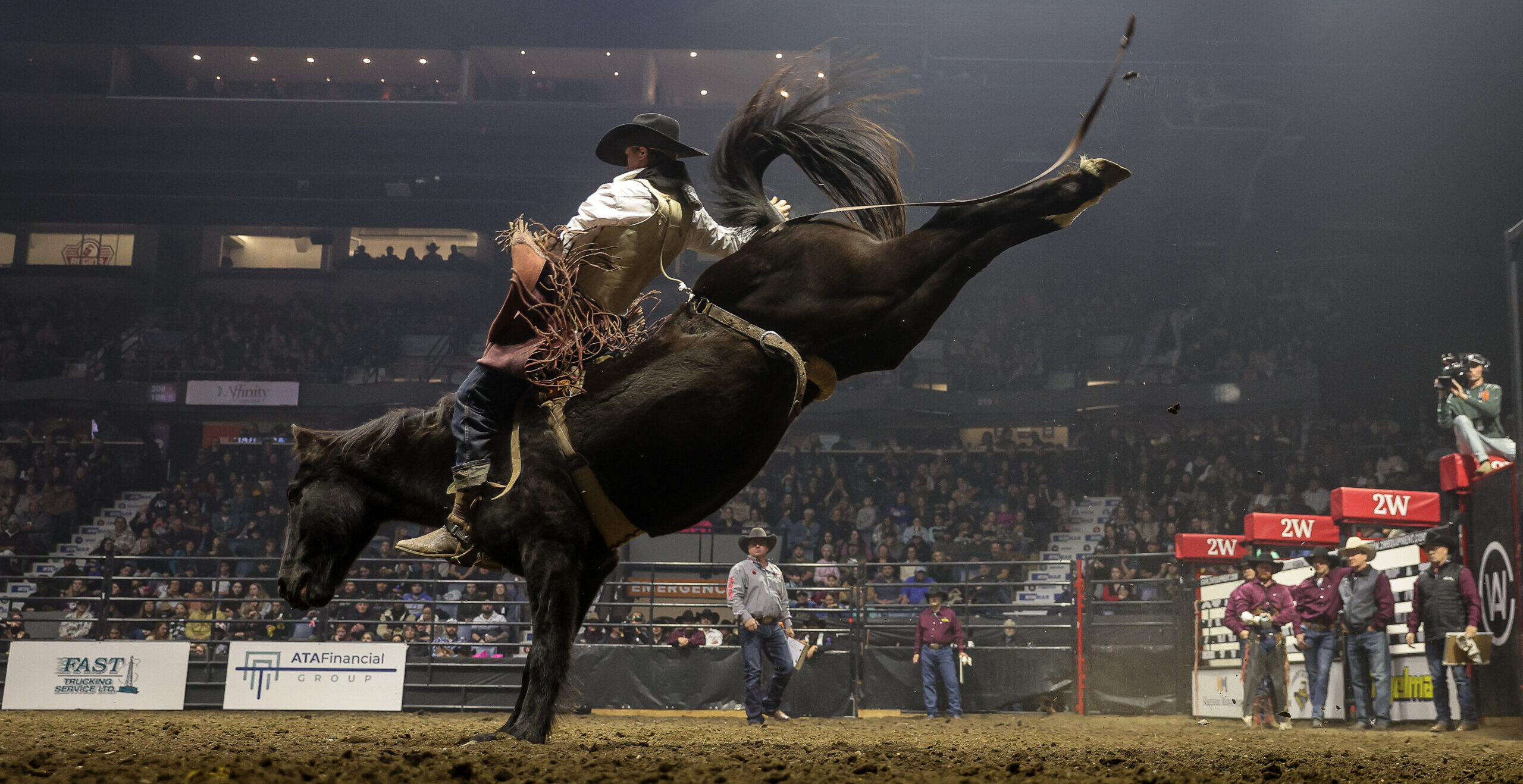 Rodeo rider on bucking horse in arena competition.