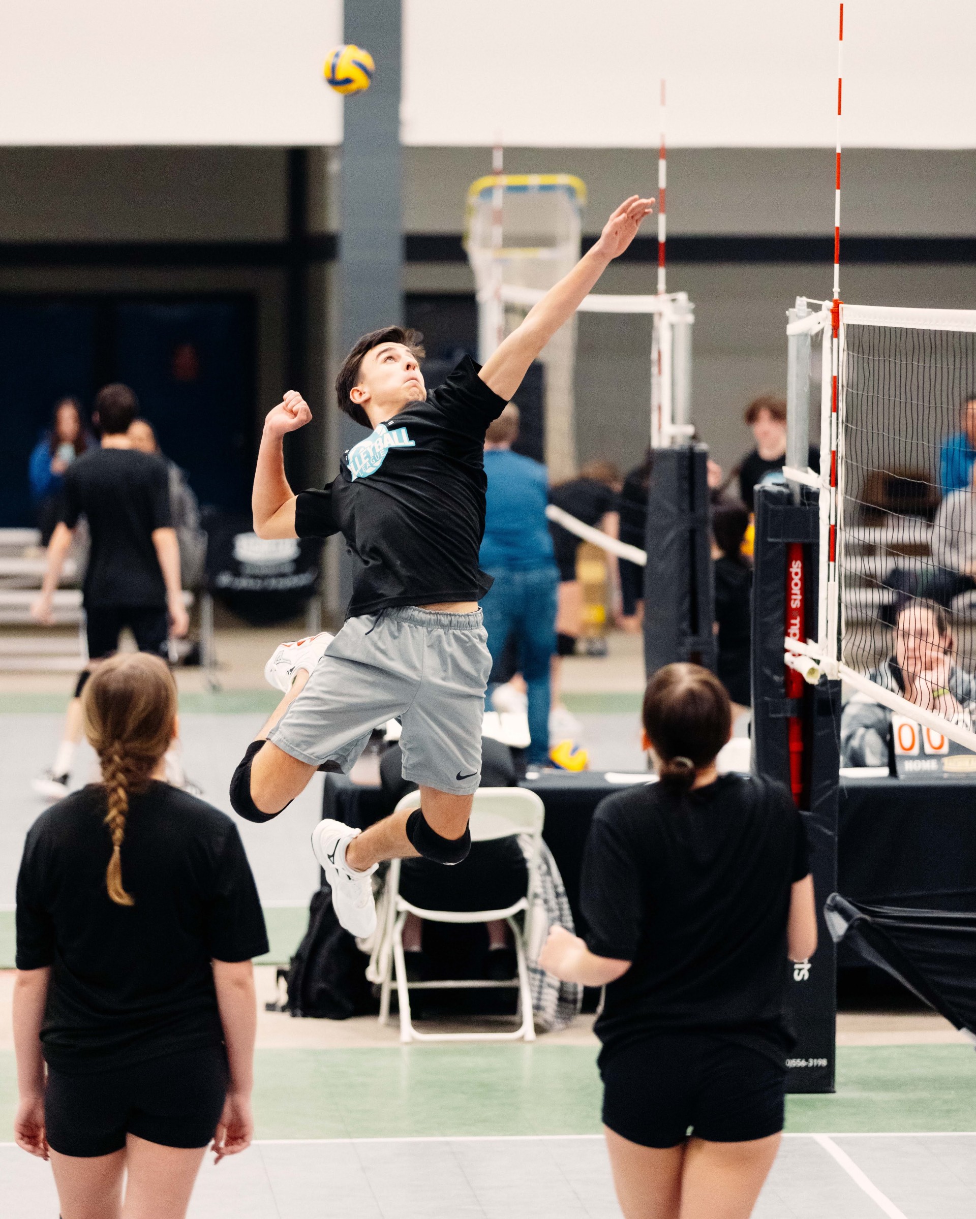 Volleyball player jumps, preparing to spike ball.