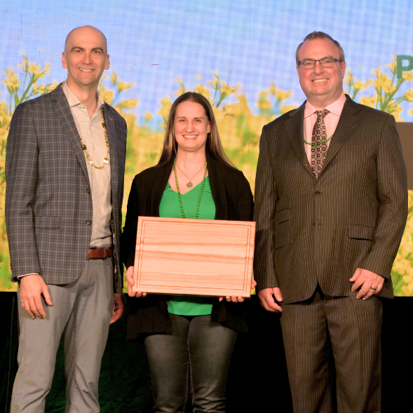 Three people at an award ceremony holding plaque.