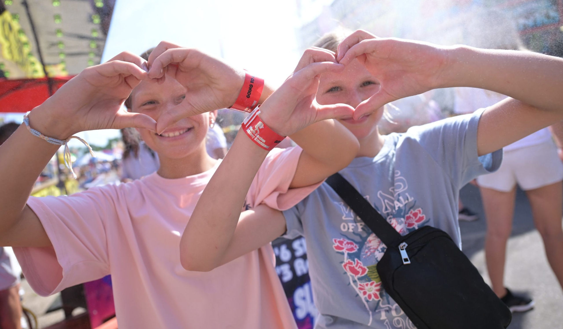 Two smiling kids making heart shapes with hands.